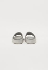 Grå glid-sandaler med åpen bak, rund tå og jevn, matt tekstur. Minimalistisk design med lett konstruksjon.