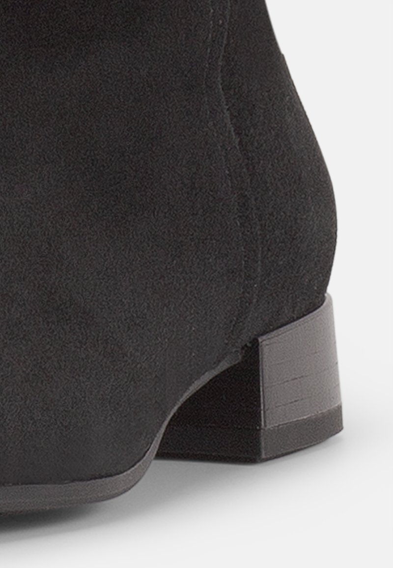 Schwarze Wildleder-Ankle-Boots mit runder Spitze und niedrigem, strukturiertem Blockabsatz. Das Material hat eine weiche, matte Oberfläche.