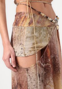 Mini skirt made of textured fabric featuring an abstract earth tone pattern; adorned with a beaded belt and side cutouts for detailing.