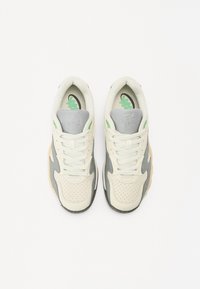 White and gray sneakers with a textured upper, green accents, and perforated details. Features a lace-up closure and cushioned insole.