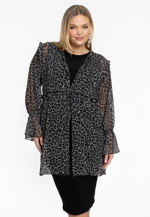 Leopardenmuster transparenter Kimono mit schwarzen Akzenten, langen Rüschenärmeln, Taillenknoten und geschichteter Gestaltung, getragen über einem schwarzen Kleid.