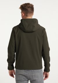 Mörkgrön huvajacka med en slät textur, med en enkel design och elastiska ärmar, bärs tillsammans med ljusgrå jeans.