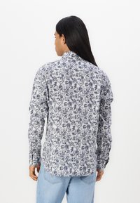 Langermet skjorte med et blått blomstermønster på hvit bakgrunn, laget av lett stoff med standard krage og knappmansjetter.