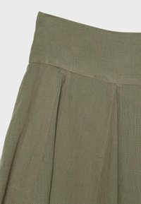 Olive green high-waist skirt with wide waistband and front pleats, made from textured lightweight fabric.