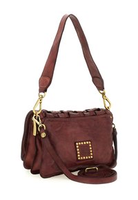 Borsa a spalla in pelle marrone con chiusure in tono oro, patch logo quadrato borchiato e tracolla lunga removibile su sfondo bianco.