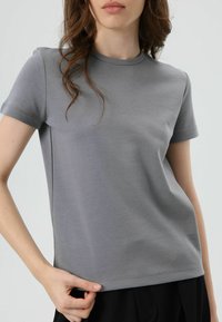 Grijs T-shirt met korte mouwen van zachte katoenmix; heeft een ronde halslijn en een aansluitend model met nette stiksels.