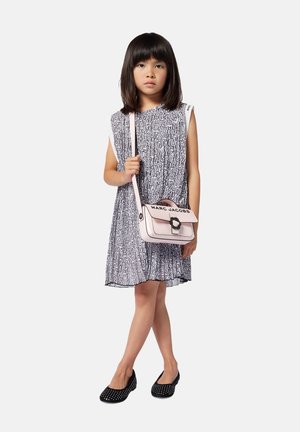 Robe à motifs noir et blanc avec des manches courtes, associée à un sac à épaule rose pâle avec un fermoir circulaire et des ballerines noires avec des clous.