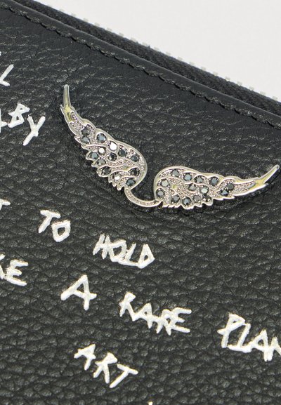 Zwart gestructureerd lederen oppervlak met een zilveren broche in de vorm van vleugels, versierd met zwarte en heldere stenen en witte handgeschreven tekst.