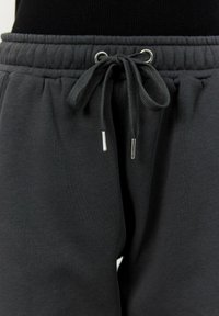 Grå sweatsbyxor med elastisk midja, justerbar dragsko och metallaccenter. Mjuk textur med en lös passform för komfort.