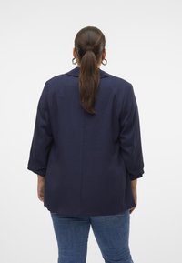 Navy blue blazer with a collar, three-quarter sleeves, and a straight cut. Textured fabric with a clean back seam detail.