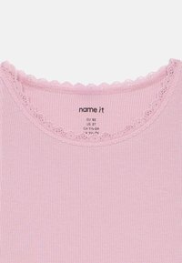 Rosa ribbet tanktop med bølget blondekant. Lappen indikerer EU-størrelse 92 og US-størrelse 2T. Myk bomullsstoff med stretch.