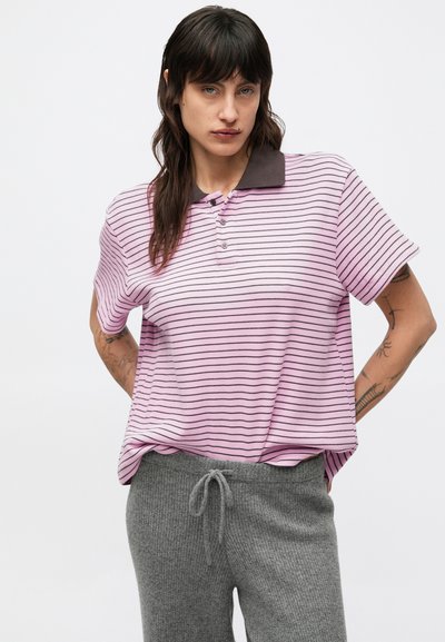 Ružová a bielo pruhovaná polokošeľa s tmavým golierom. Krátke rukávy, voľný strih, nosená so sivými nohavicami na šnúrku.