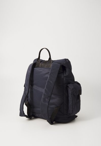 Námorný batoh vyrobený z odolnej tkaniny s polstrovanými ramennými popruhmi, hornou rukoväťou a bočnou vreckom. Má elegantný, minimalistický dizajn.