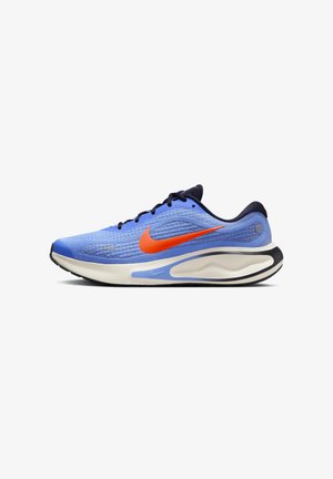 Niebieski but do biegania marki Nike z pomarańczowym logo, czarnymi sznurowadłami i amortyzowaną białą podeszwą z niebieskimi i czarnymi akcentami, pokazany z boku.