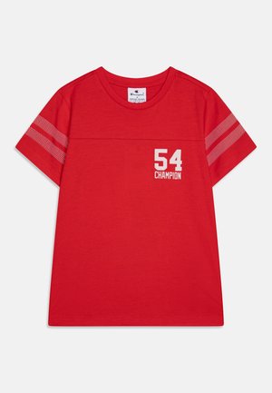 Rotes T-Shirt mit kurzen Ärmeln und weißem "54 CHAMPION" Schriftzug auf der Brust sowie zwei weißen gepunkteten Streifen auf jedem Ärmel.