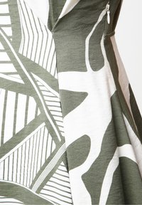 Vihreä ja valkoinen mekko, jossa on abstrakteja lehtikuosisia, pehmeä tekstuuri ja sivuvetoketjullinen sulkeminen.