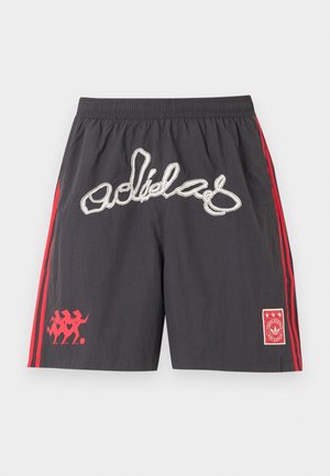 Pantaloncini sportivi neri con strisce rosse ai lati, grande scritta stilizzata "adidas" bianca sulla parte anteriore e loghi grafici rossi su entrambe le gambe.