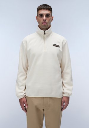 Cremefarbener Fleece-Pullover mit hohem Kragen, Viertel-Reißverschluss und einem kleinen schwarzen Logopatch auf der Brust. Lässige Passform und glatte Textur.
