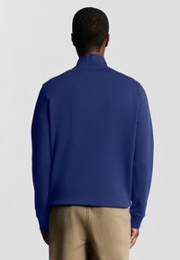 Felpa blu navy con collo alto, polsini a costine e una trama liscia. Appare aderente senza motivi o decorazioni visibili.