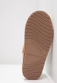 Calzature marroni resistenti all'acqua con suola in gomma testurizzata caratterizzata da scanalature curve. Logo "EMU Australia" impresso sul lato.