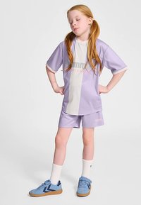 Fioletowy i biały sportowy strój składający się z krótkiego topu z krótkim rękawem i szortów. Buty są niebieskie z brązowymi podeszwami. Zestaw zawiera białe skarpetki.