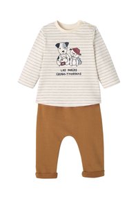 Gestreiftes Langarmoberteil in Creme mit einem Hund- und Bären-Print, kombiniert mit braunen Hosen mit hochgerollten Säumen, aus weichem Stoff.