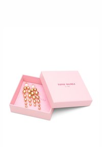 Kultakinnoiset roikkuvat korvakorut, joissa on laskeutuva muotoilu, pyöreitä helmiä ja helmiä korostuksina. Ne on esitelty vaaleanpunaisessa laatikossa, jossa on kohopainettu teksti.