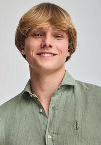 Camicia di lino verde chiaro con una sottile texture, design con bottoni e logo ricamato sul lato sinistro del petto.