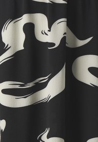 Tessuto nero con motivi astratti a spirale avorio; la superficie texture aggiunge profondità. Il design presenta forme fluide e linee morbide.