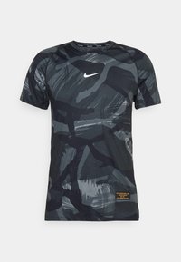 Camiseta Nike de manga corta en negro y gris con patrones abstractos de pinceladas, cuello redondo y un pequeño logo blanco en el pecho.