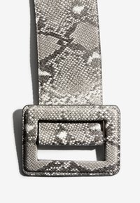 Cinturón con patrón de piel de serpiente en gris y blanco. Cuero texturizado con hebilla rectangular y maciza. Material duradero con detalles sutiles.