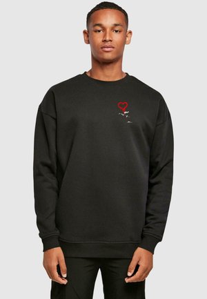 Black sweatshirt with a round neckline, ribbed cuffs, and hem. Features red heart graphic and white detailed design on the chest area.