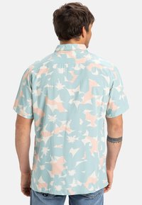 Camicia a maniche corte di colore azzurro chiaro con motivi astratti in rosa e bianco; tessuto leggero; colletto standard; vestibilità comoda.