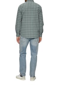 Groen en marineblauw geruite shirt met lange mouwen en een button-down kraag; gecombineerd met lichtblauwe jeans en witte sneakers. Achteraanzicht weergegeven.