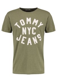 Olivově zelené bavlněné tričko s krátkými rukávy a kulatým výstřihem; s velkým bílým textem "TOMMY NYC JEANS" v kruhovém designu.