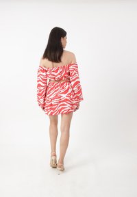 Off-shoulder crop top en rokset in rood-wit zebra print, met gelaagde ruffles en een elastische tailleband. Draag het met bandjeshakken.