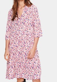 Květinové šaty s růžovým pozadím, s výstřihem do V, tříčtvrtečními rukávy a vrstveným lemem v červené, modré a fialové barvě.