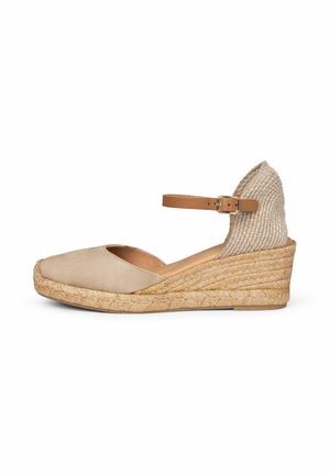 Zapato espadrille con cuña beige con suela de yute tejido, puntera cerrada y una correa ajustable para el tobillo en color camel con hebilla metálica.