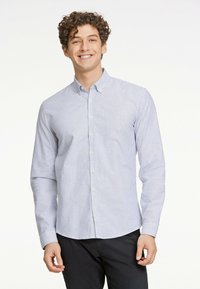 Pasiasty, długi rękaw, wykonany z lekkiego materiału; posiada kołnierzyk zapinany na guziki, pionowe niebiesko-białe paski i zaokrąglony dół.