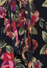 Tessuto floreale con grandi fiori rosa e rossi e foglie verdi su uno sfondo nero; include legacci in tessuto con una texture liscia.