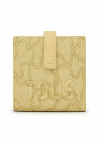 Billetera amarilla texturizada con cierre de solapa y botón. Presenta un sutil patrón estampado y el nombre de la marca "Tous" mostrado de manera prominente.