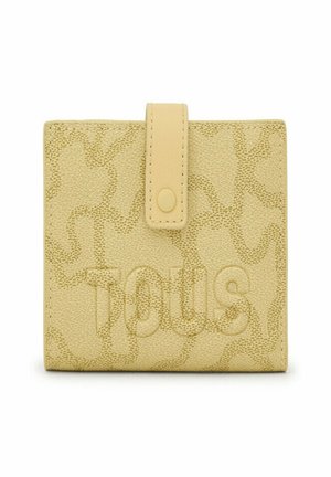 Billetera amarilla texturizada con cierre de solapa y botón. Presenta un sutil patrón estampado y el nombre de la marca "Tous" mostrado de manera prominente.
