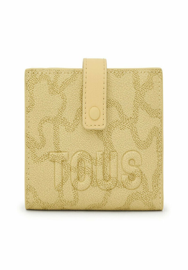 Billetera amarilla texturizada con cierre de solapa y botón. Presenta un sutil patrón estampado y el nombre de la marca "Tous" mostrado de manera prominente.