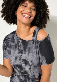 T-shirt grigio tie-dye con design a spalle scoperte. Presenta un sorriso in strass sul davanti, maniche corte e una vestibilità rilassata.