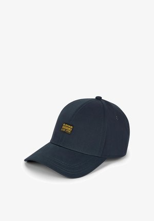 Casquette de baseball bleu marine foncé avec une visière incurvée et un petit écusson logo G-Star Originals jaune et noir sur le panneau avant.