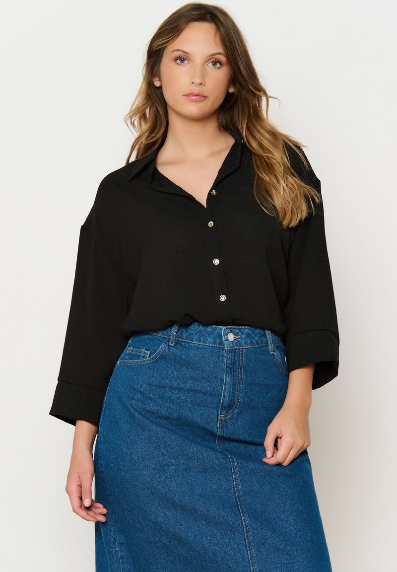 Black button-up shirt with a collar and wide sleeves, paired with a high-waisted blue denim skirt, featuring a front button closure.
