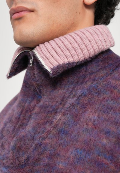 Purple and blue marled knit sweater with a high collar featuring a ribbed pink edge and a silver zipper at the neckline, showing soft texture.