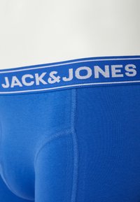 Modré bavlněné boxerky s modrým páskem. Páska má bílé písmo s názvem značky "JACK&JONES".