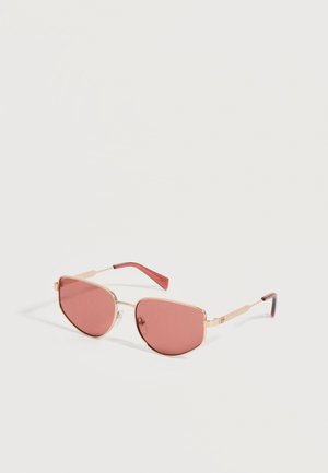 Lunettes de soleil à monture dorée avec verres teintés roses et branches rouges, présentées sur fond blanc.