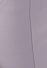 Tessuto viola con una trama fine e strutturata, caratterizzato da linee diagonali e una leggera lucentezza. Include un dettaglio di cucitura lungo il bordo.